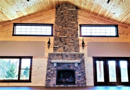 Floor to ceiling stone faced fireplace with large windows to let in the natural light